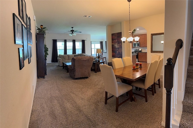 dining room with light carpet, visible vents, and ceiling fan with notable chandelier