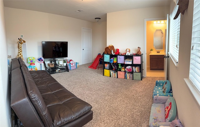 recreation room featuring carpet floors, a healthy amount of sunlight, a sink, and visible vents
