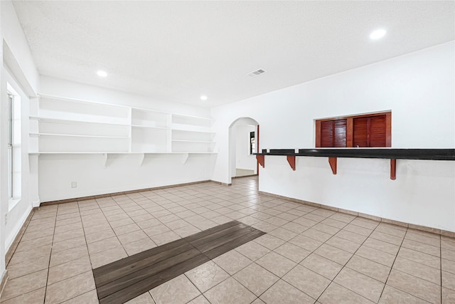 unfurnished room featuring recessed lighting, arched walkways, visible vents, and light tile patterned floors