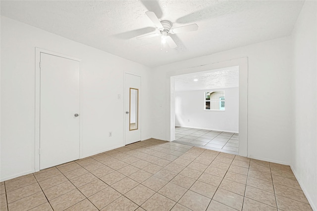 unfurnished room with a ceiling fan, a textured ceiling, and light tile patterned floors