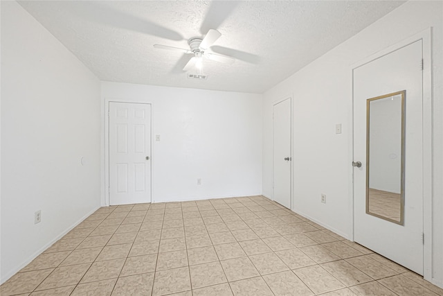 spare room featuring light tile patterned flooring, a textured ceiling, a ceiling fan, and visible vents