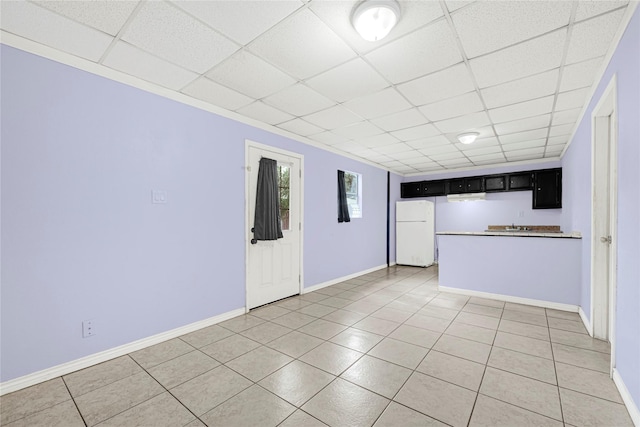 unfurnished living room featuring baseboards, a drop ceiling, and light tile patterned floors