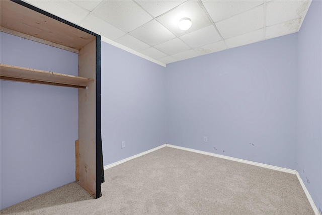 unfurnished bedroom featuring baseboards, carpet floors, and a drop ceiling