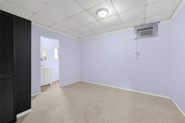 interior space with baseboards, a drop ceiling, light colored carpet, and connected bathroom