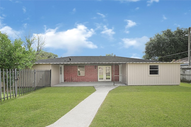 view of front of home with french doors, a front lawn, fence, brick siding, and a patio area