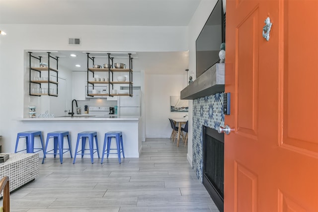 bar featuring recessed lighting, visible vents, a sink, freestanding refrigerator, and light wood-style flooring