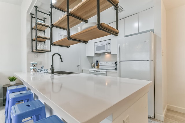 kitchen featuring open shelves, a sink, white appliances, a peninsula, and white cabinetry