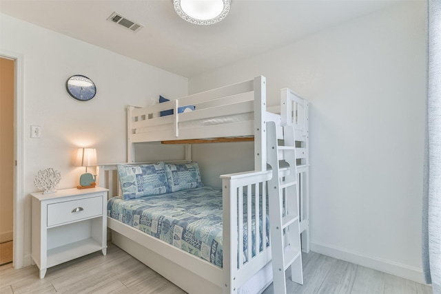 bedroom featuring light wood-style flooring, visible vents, and baseboards