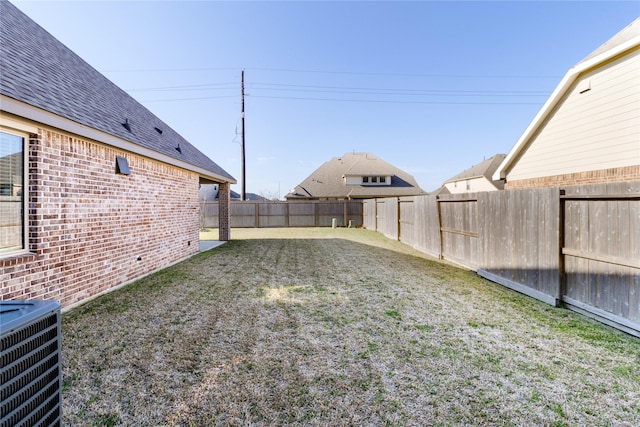 view of yard with a fenced backyard and central AC unit