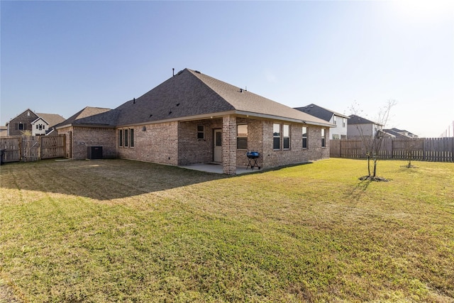 back of property featuring a lawn, a shingled roof, a fenced backyard, a patio, and brick siding