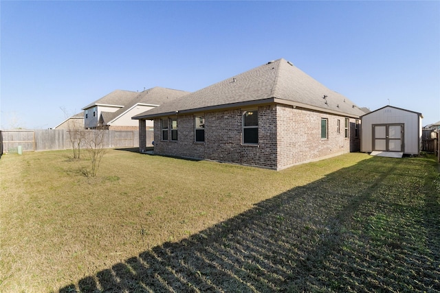 exterior space with a storage shed, a lawn, a fenced backyard, an outbuilding, and brick siding