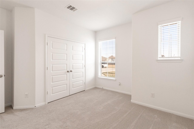 unfurnished bedroom featuring baseboards, carpet flooring, multiple windows, and visible vents