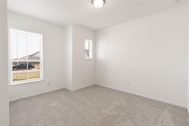 unfurnished room featuring light carpet and baseboards