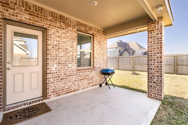 entrance to property with brick siding, fence, and a patio
