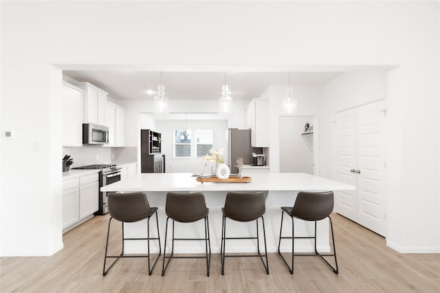 kitchen with light wood-type flooring, a kitchen breakfast bar, backsplash, and appliances with stainless steel finishes