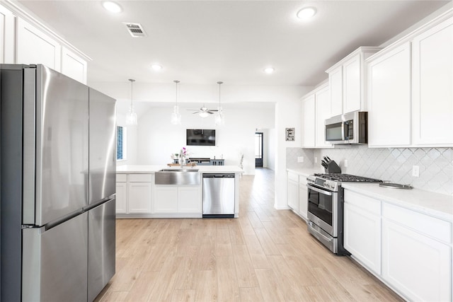 kitchen featuring stainless steel appliances, light countertops, visible vents, a ceiling fan, and a sink