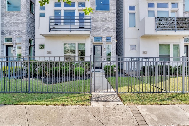 property entrance with a gate, fence, brick siding, a yard, and stucco siding