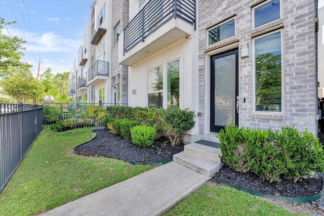 doorway to property featuring fence and a lawn