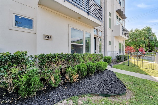 exterior space with stucco siding, a yard, and fence