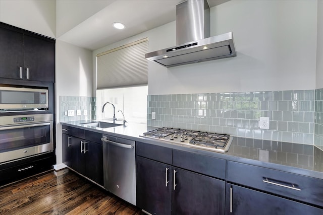kitchen with tasteful backsplash, a sink, stainless steel appliances, dark wood finished floors, and wall chimney exhaust hood