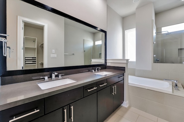bathroom with double vanity, a shower stall, tile patterned flooring, and a sink