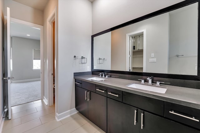 bathroom featuring double vanity, tile patterned floors, baseboards, and a sink