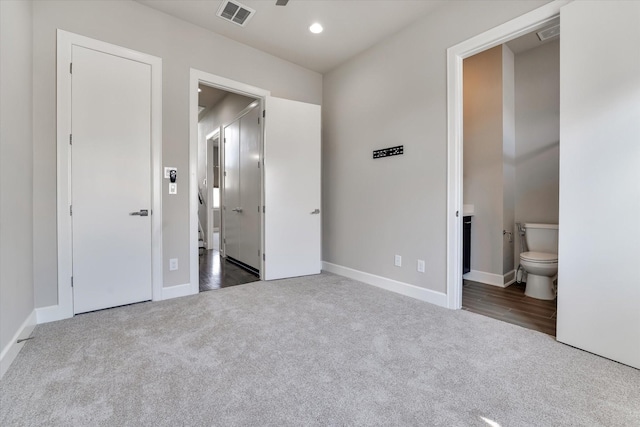 unfurnished bedroom featuring baseboards, ensuite bathroom, visible vents, and carpet