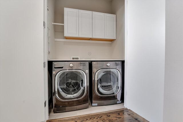 washroom with washing machine and clothes dryer, light wood-type flooring, and cabinet space