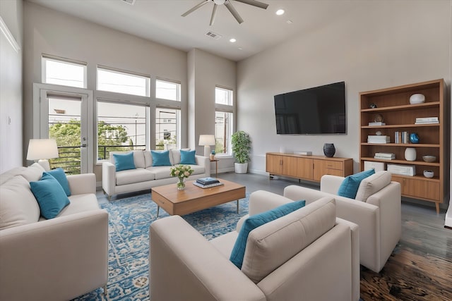 living area with a ceiling fan, a high ceiling, dark wood-style flooring, visible vents, and recessed lighting