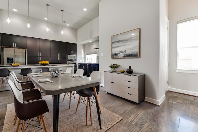 dining area with a towering ceiling, baseboards, wood finished floors, and recessed lighting