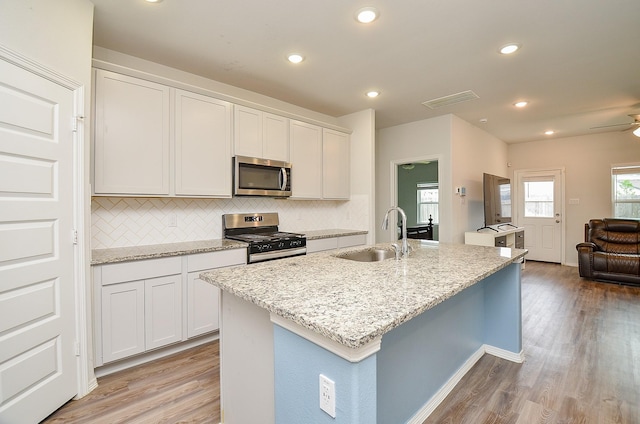 kitchen featuring light wood-type flooring, a sink, backsplash, and stainless steel appliances