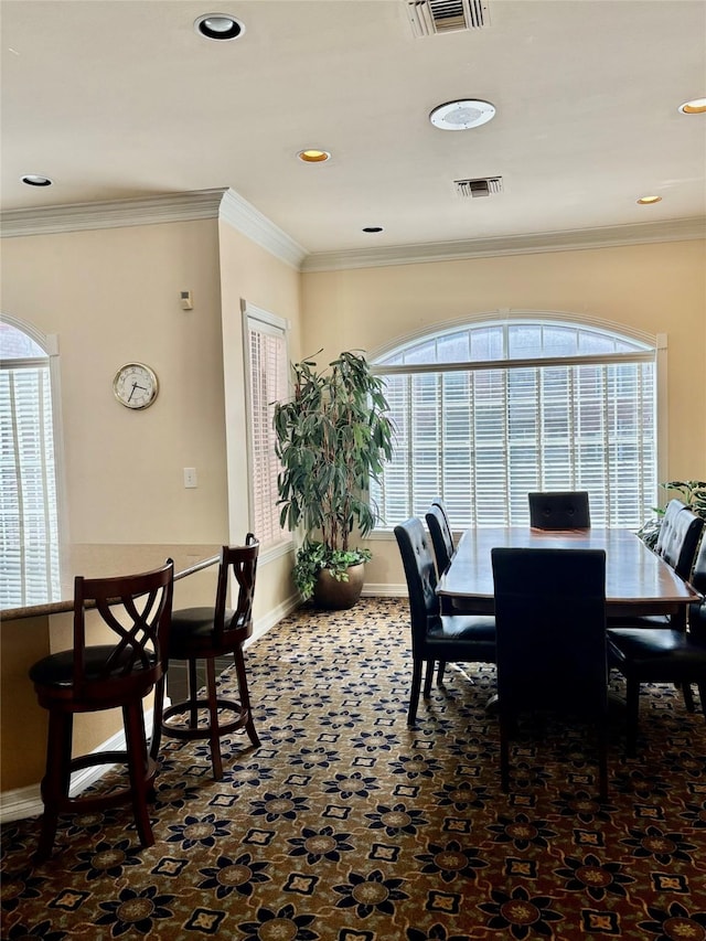 dining room featuring visible vents, baseboards, crown molding, and a healthy amount of sunlight