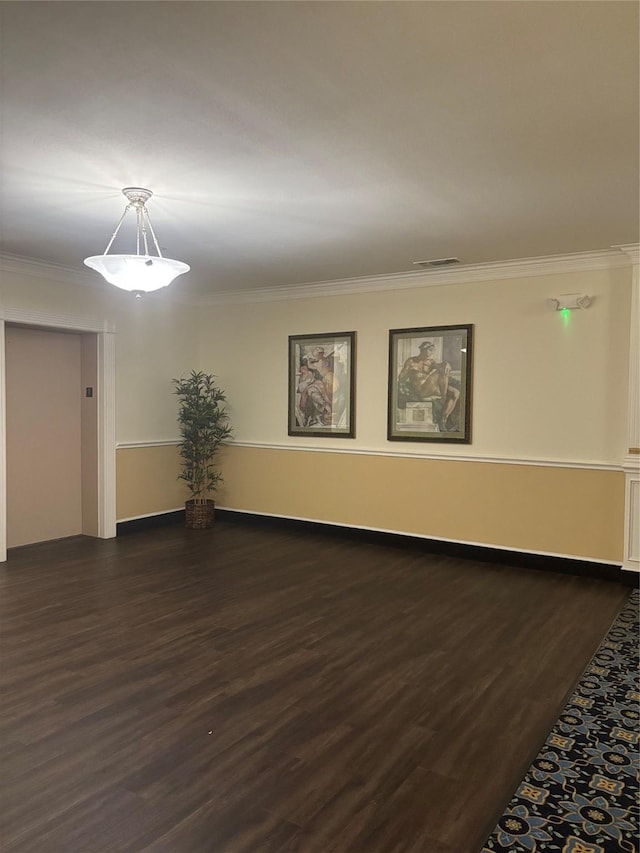 spare room featuring baseboards, ornamental molding, dark wood-style flooring, and visible vents