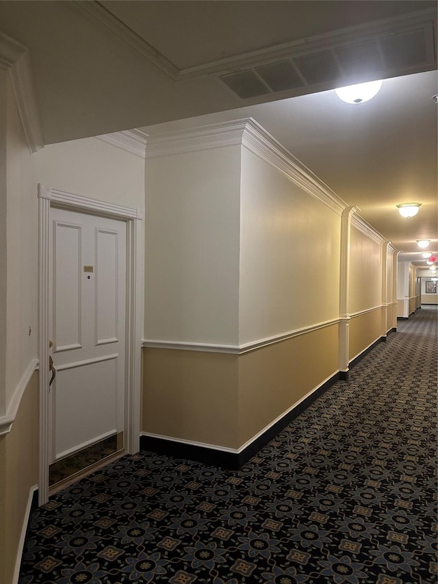 hallway with dark colored carpet, ornamental molding, and baseboards