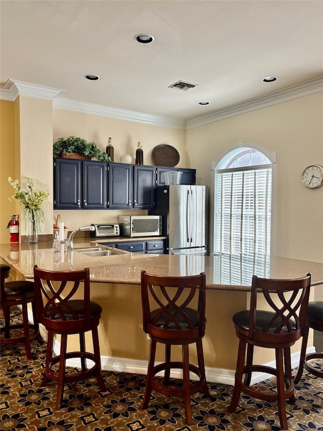 kitchen featuring appliances with stainless steel finishes, a sink, visible vents, and a kitchen bar