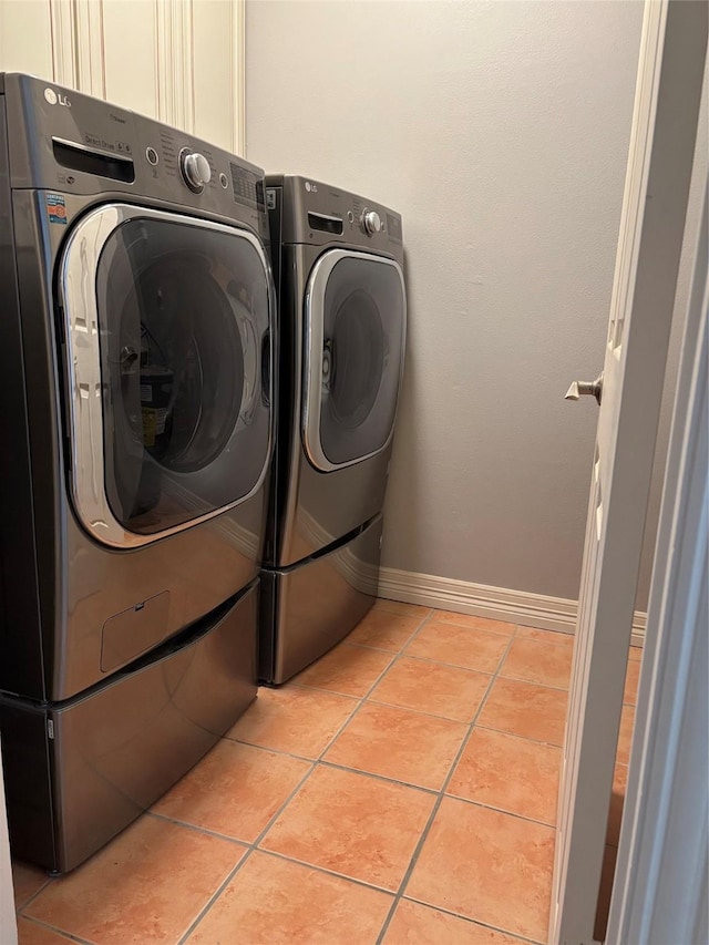 laundry area with washing machine and clothes dryer, baseboards, and light tile patterned floors