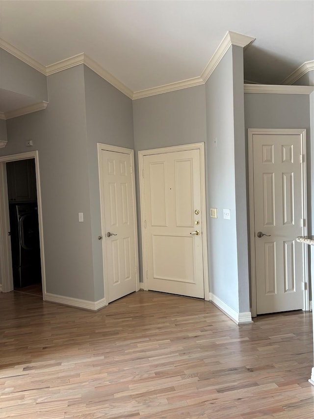 foyer with baseboards, ornamental molding, and light wood-style floors