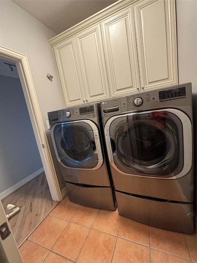 washroom featuring light tile patterned floors, baseboards, cabinet space, and washer and dryer