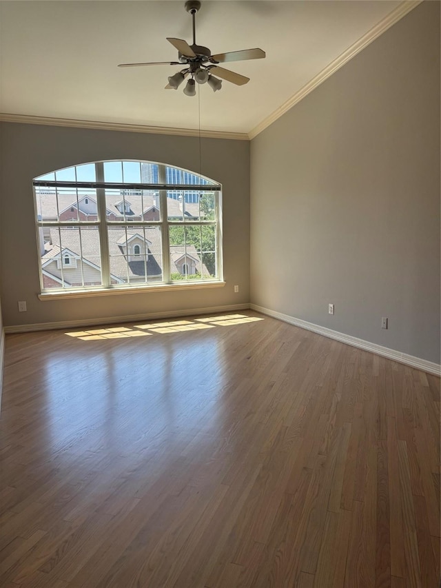 spare room featuring crown molding, a ceiling fan, baseboards, and dark wood-style floors