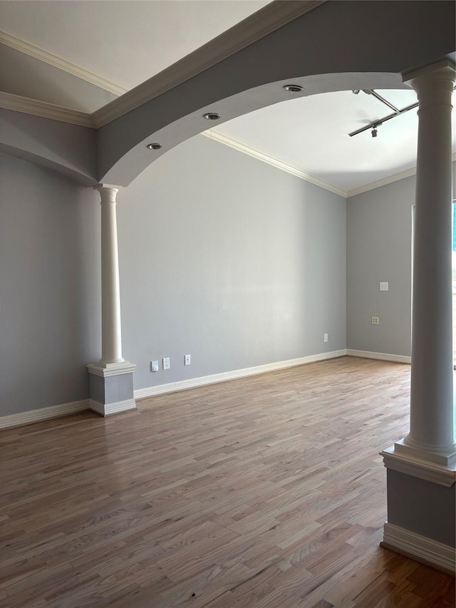 unfurnished living room with track lighting, ornamental molding, decorative columns, wood finished floors, and baseboards