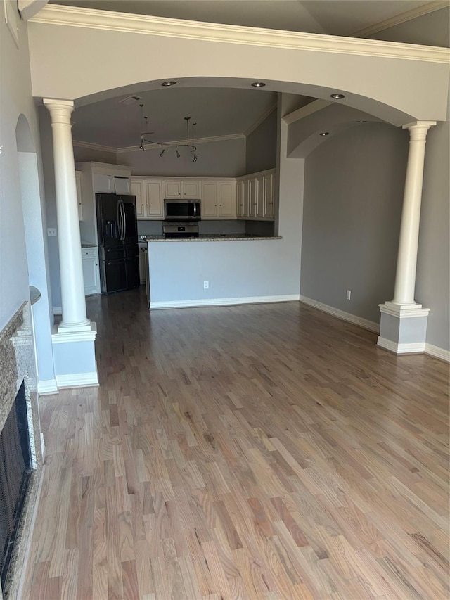 unfurnished living room featuring track lighting, light wood finished floors, a fireplace, decorative columns, and ornamental molding