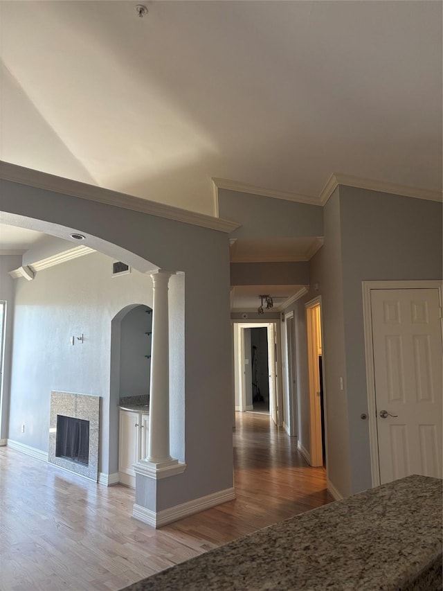 interior space with visible vents, ornamental molding, wood finished floors, baseboards, and arched walkways