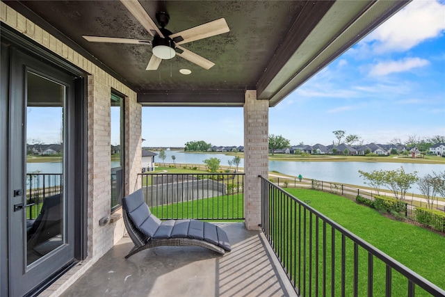 balcony with a water view, a residential view, and ceiling fan