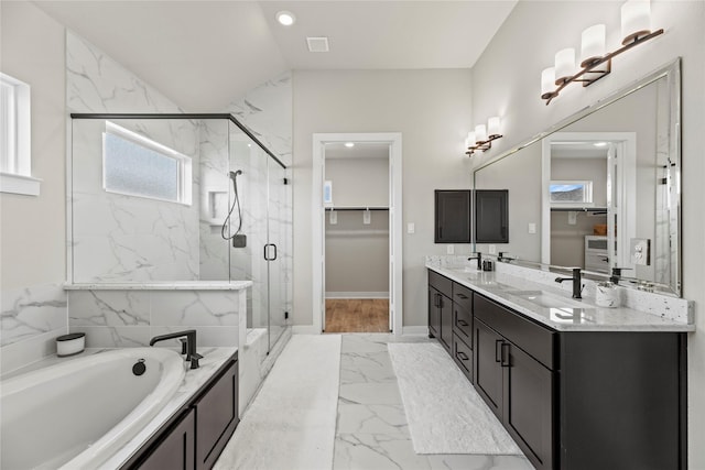 full bathroom featuring a spacious closet, marble finish floor, a sink, and plenty of natural light