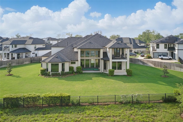 rear view of house featuring roof with shingles, a yard, a residential view, and a fenced backyard