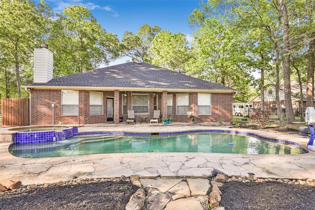view of pool with a pool with connected hot tub, a patio, and fence