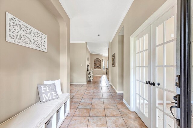 hall featuring baseboards, light tile patterned floors, and crown molding
