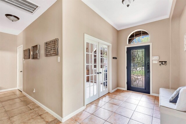 entryway with french doors, light tile patterned flooring, baseboards, visible vents, and crown molding