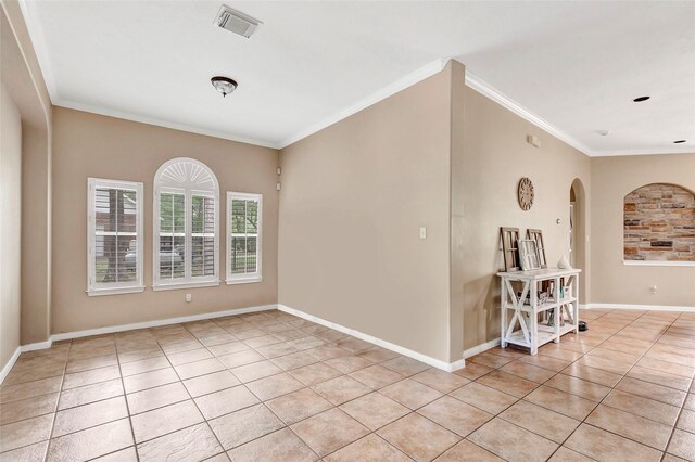 spare room featuring visible vents, ornamental molding, light tile patterned floors, arched walkways, and baseboards