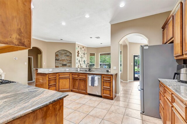 kitchen with brown cabinets, appliances with stainless steel finishes, light tile patterned floors, and a sink